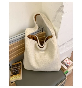 Close-up of white fleece tote bag with brown lining and OUR FAVE logo on a gray seat