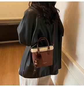 Gros plan du sac seau en daim marron avec bordure en polaire blanche et breloques
