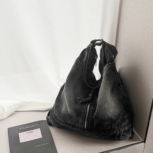 Detail view of washed denim tote bag with decorative zippers and retro worn texture