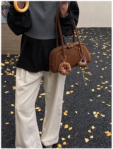 Detail of a brown suede Boston bag with long handles and decorative cute charms