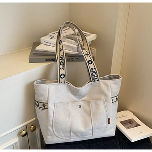 Detail of canvas tote bag featuring floral jacquard straps and vintage SJCHAO label