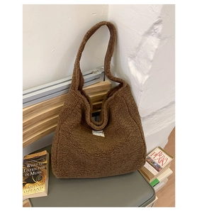 Detail of soft brown sherpa tote bag with OUR FAVE label on a minimalist chair