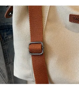 Detail of adjustable brown woven shoulder strap with metal buckle on canvas tote bag