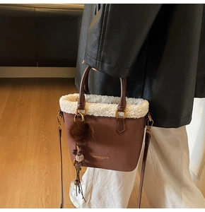 Détail du sac seau en similicuir marron avec bordure en fourrure blanche et logo doré