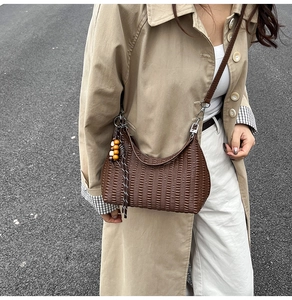 Close-up of brown textured shoulder bag with colorful wooden beads and silver metal buckles