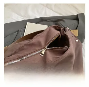 Close-up of durable silver metal zipper and rivet details on brown canvas tote bag