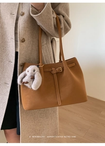 Detail of vintage brown matte leather tote bag with elegant bunny plush charm and metal buckle