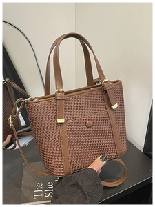 Vista dettagliata della borsa tote marrone intrecciata con cinturini in pelle e metallo