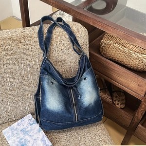 Detail of vintage washed denim crossbody bag featuring functional pockets and zippers