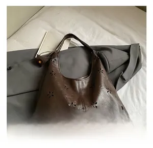 Détail de motifs floraux découpés au laser sur un sac à bandoulière en similicuir brun