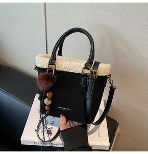 Détail du sac seau noir avec bordure en peau de mouton crème et pompon décoratif