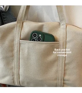 Detail of the back pocket on a khaki canvas tote bag showing storage for a smartphone