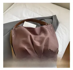 Detail view of large canvas tote bag with brown leather handles and silver rivet accents