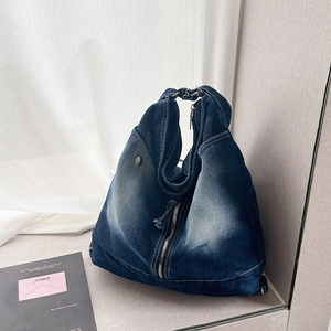 Detail of dark blue denim tote bag featuring white contrast stitching and metal zipper