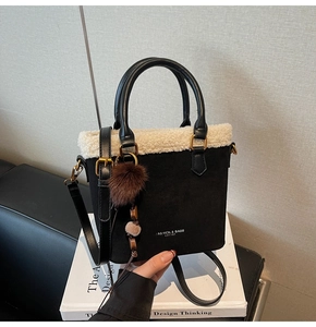 Détail du sac à main en daim noir avec bordure en simili mouton et pompon marron