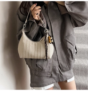 Close-up of cream woven hobo bag with wooden bead charm and brown rope detail
