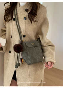 Detail of retro bucket bag with decorative stitching and brown faux fur pompom charm