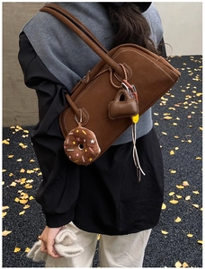 Detailed texture of dark brown frosted suede shoulder bag with creative plush charms