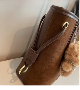 Detail of brown leather underarm bag with gold ring and plush bear charm accessory