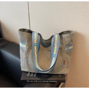 Detail of grey canvas tote bag featuring SICHHAO patterned webbing handles and front pocket