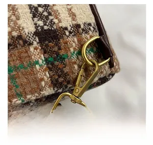 Gros plan sur le tissu en tweed à carreaux, crochet doré antique et sangle en cuir