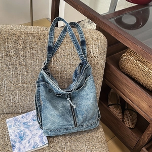 Detail of light blue washed denim tote bag with vintage buttons on a woven sofa