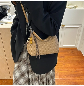 Detail of light brown pleated hobo bag with wooden bead charm and woven rope knot