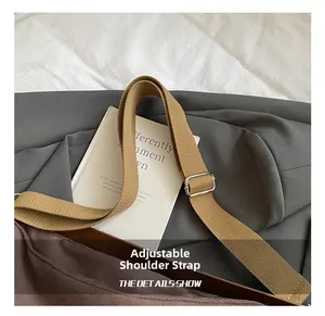 Detail of adjustable brown canvas shoulder strap with silver metal buckle on a tote bag