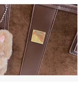 Close-up of brown suede and leather tote bag featuring a glossy square gold metal buckle