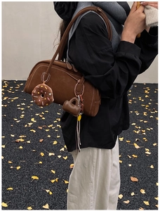 Detail of vintage brown suede shoulder bag with plush heart and donut charm accessories