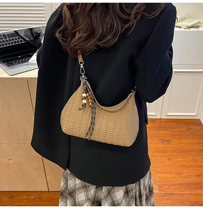 Detail of hobo shoulder bag featuring pleated texture and ethnic wooden bead pendant