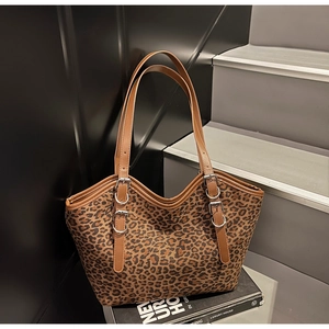 Dettaglio della borsa tote leopardata con cinturini in pelle marrone e fibbie d'argento