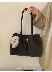 Detail of a black retro matte tote bag with slim shoulder straps and a cute rabbit pendant