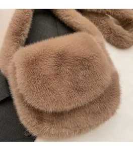 Detail of plush camel faux fur crossbody bag placed on a textured grey blazer