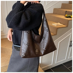 Détail du motif floral ajouré sur le grand sac cabas en cuir marron foncé