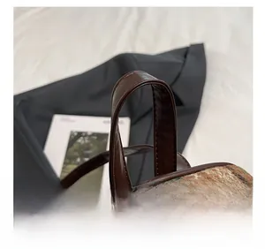 Détail de la poignée en similicuir marron et du tissu en tweed à carreaux du sac