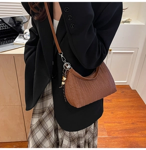 Detail of a brown crescent shoulder bag with pleated texture and wooden bead pendant