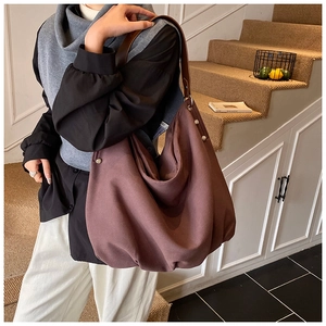 Deep brown canvas tote bag detail featuring premium leather shoulder strap and metal rivets