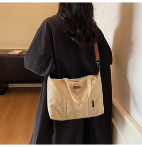 Detail of beige canvas tote bag with brown adjustable shoulder strap on a model