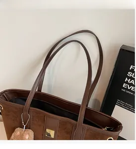 Close-up of vintage brown tote bag with leather handles and cute plush kitten charm