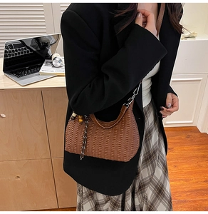 Brown pleated half-moon shoulder bag with wooden bead charm on a chic office model