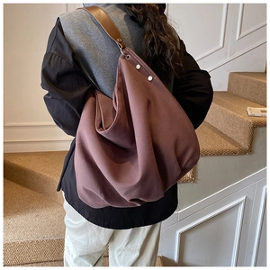 Detail of coffee canvas tote with brown leather strap and silver rivet accents