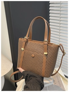 Dettaglio della borsa tote intrecciata marrone con manici in pelle e finiture in metallo dorato