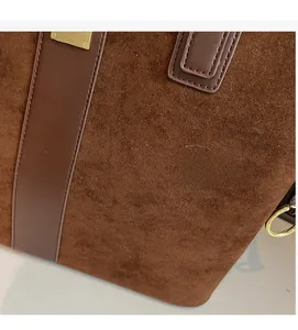 Detailed close-up of dark brown suede tote bag with leather trim and gold metal rings
