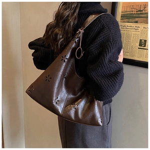 Détail du grand sac cabas marron foncé avec motifs floraux ajourés porté à l'épaule