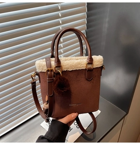 Détail d'un sac seau en suédine marron avec bordure en fourrure blanche et pompon