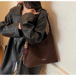 Detail of dark brown suede shoulder bag with a cute red polka dot bear charm