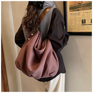 Detail of the large canvas tote bag showing wide shoulder straps and metal snap button closure