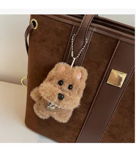 Detailed view of a brown plush dog charm with pearl bone necklace on a bucket bag