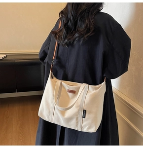 Detailed back view of a cream canvas tote bag with brown straps worn in a home setting